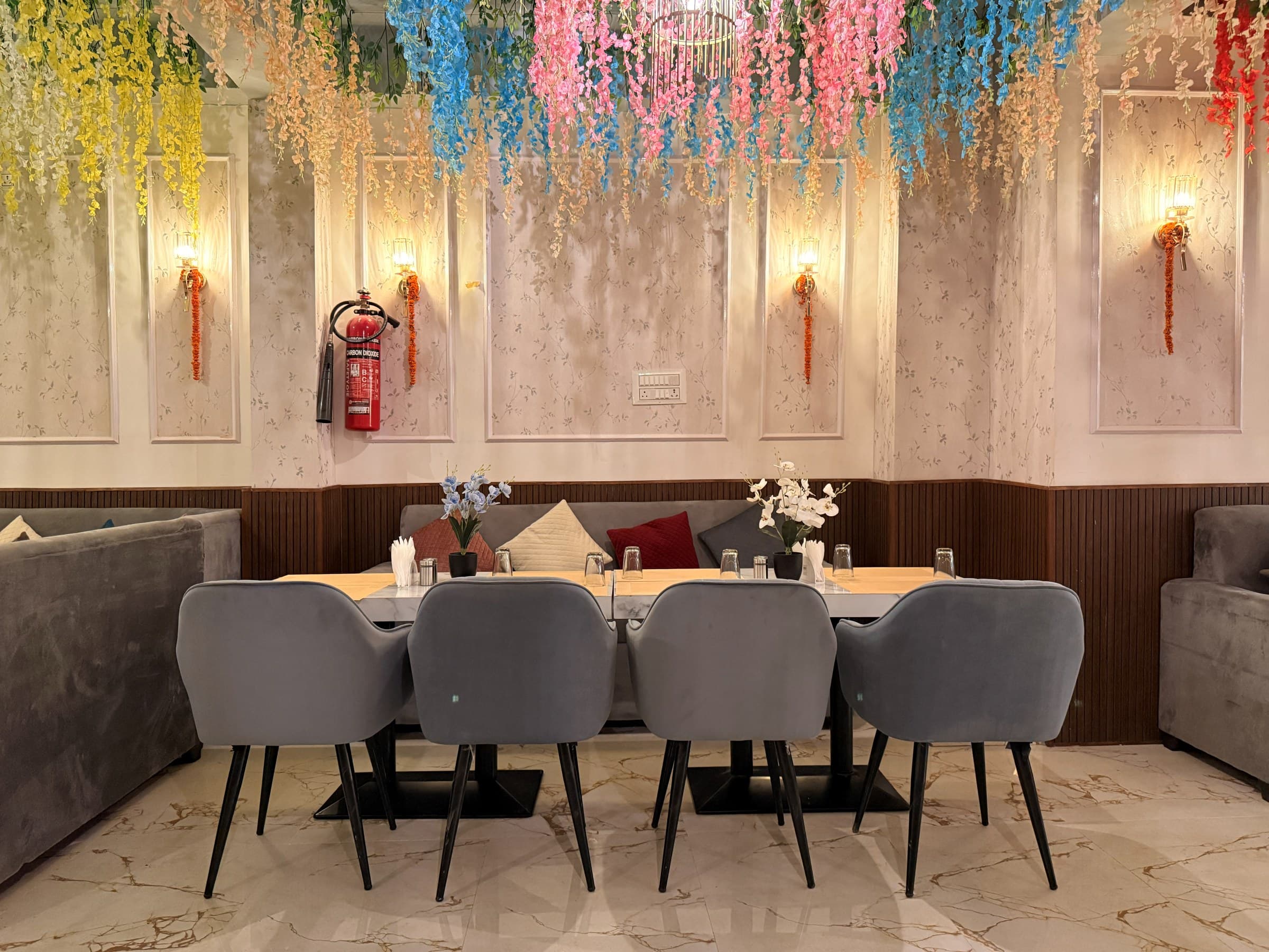 Symmetrical velvet booths beneath a canopy of pastel flowers at The Silver Spoon